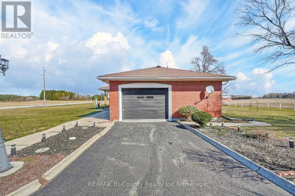 Red brick garage with single roll-up door and asphalt driveway - 568 7th Concession Enr Road Norfolk