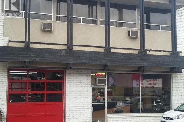 Close-up of commercial building facade showing red garage door, glass storefront, and upper windows. - 568 Seymour Street 260 6th Avenue Street, Kamloops