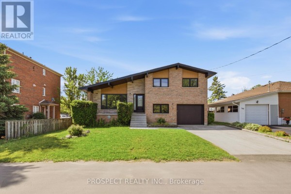 Front exterior of a split-level house with a sloped roof, brick and stone facade. - 568 Simcoe Street, Collingwood