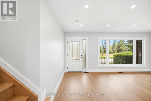 Interior entryway with hardwood floors, white walls, a glass-paneled front door, and a large window. - 568 Simcoe Street, Collingwood