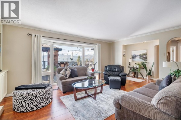 Living room with a fireplace, built-in shelving, a television, and artwork on the wall. - 5687 Somerset Avenue, Peachland