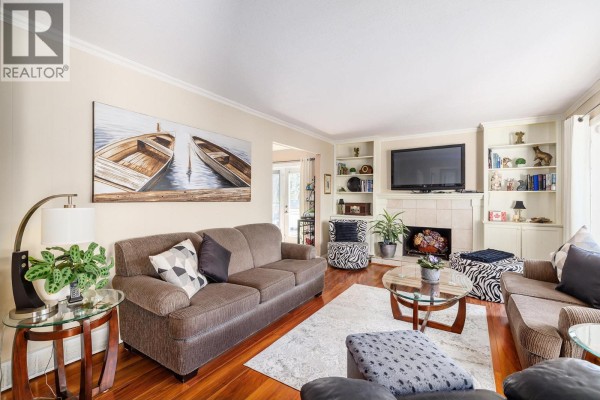 Living room with multiple seating areas, a glass coffee table, and an open doorway to a dining area. - 5687 Somerset Avenue, Peachland