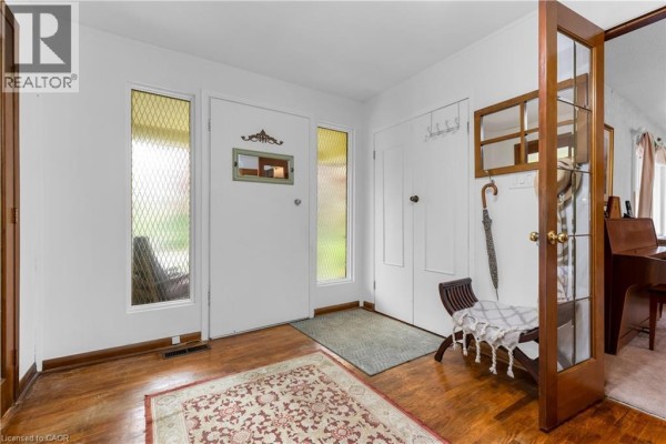 The entryway features hardwood floors, a white door, a bench, an umbrella stand, and a glass-paneled door. - 569 Crane Court, Burlington