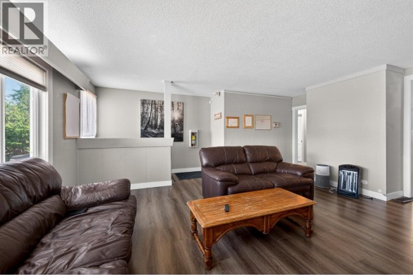 Living room with two brown leather sofas, a wooden coffee table, and a doorway leading to a hallway. - 569 Fortune Drive, Kamloops