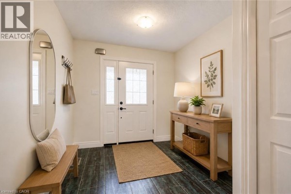 Interior entryway with a bench, round mirror, console table, and a jute rug on dark flooring. - 569 Violet Street, Waterloo