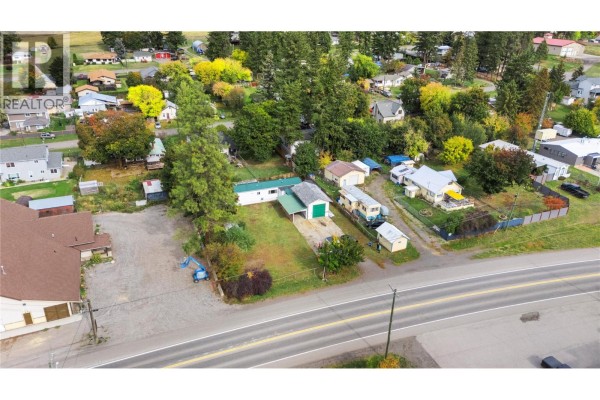 Aerial view of houses and mobile homes along a highway, surrounded by trees and hills. - 5694 97 Highway, Falkland