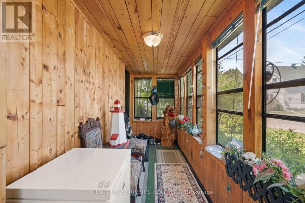 A wood-paneled sunroom with large windows and decorative items like a lighthouse. - 5694 Duncan Street, South Dundas
