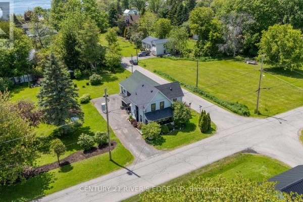 Aerial view of a light-blue house with a dark roof surrounded by green lawn and trees. - 5694 Duncan Street, South Dundas