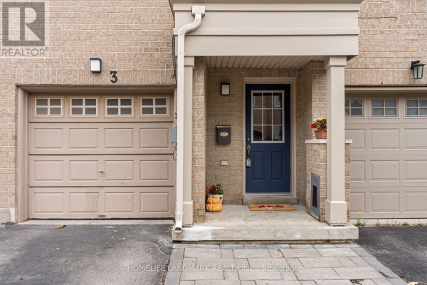 Close-up of the townhouse entrance with a blue door, mailbox, and two beige garages. - 57 - 3 Brisby Mews, Toronto
