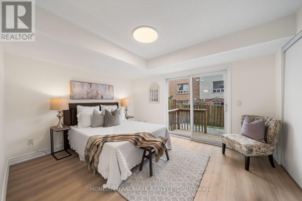 Bedroom with a queen-size bed, wooden floors, sliding glass door to a deck, and a chair. - 57 - 3 Brisby Mews, Toronto