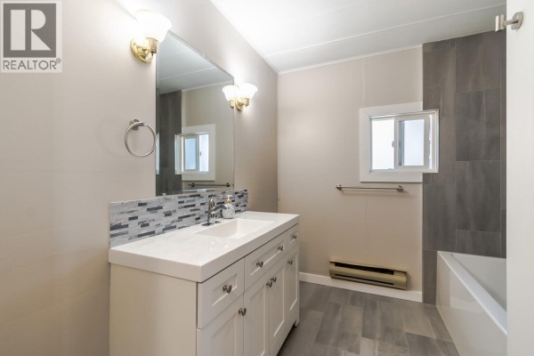 Open front door of a blue house revealing entryway with table and rug. - 57 12th Avenue, Lillooet