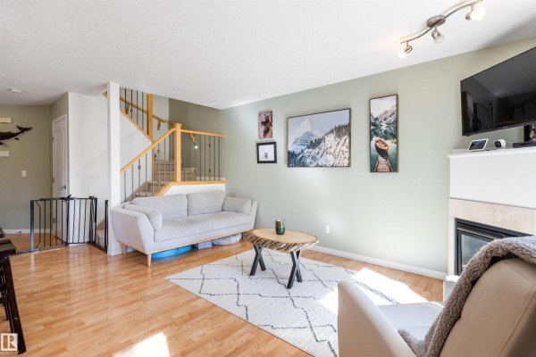 Living room with light green walls, a grey sofa, staircase, and a view into the dining area. - #57 133 Eastgate Wy, St  Albert