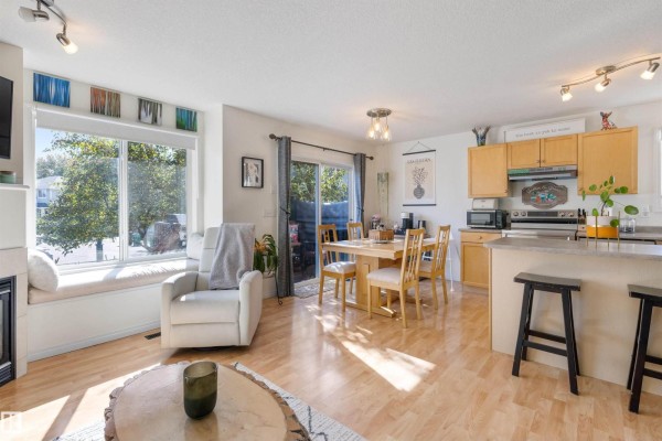 Dining area and kitchen with light wood cabinets, island seating, and a sliding glass door to the outside. - #57 133 Eastgate Wy, St  Albert