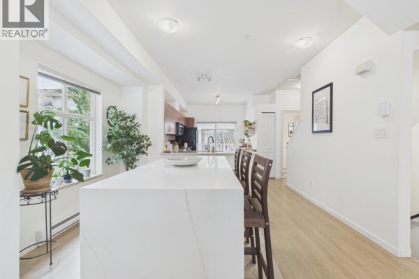 Kitchen island with marble countertop, wooden stools, and cabinets in the background. - 57 935 Ewen Avenue, New Westminster
