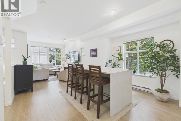 Open-concept living and kitchen area with island seating and views of greenery. - 57 935 Ewen Avenue, New Westminster