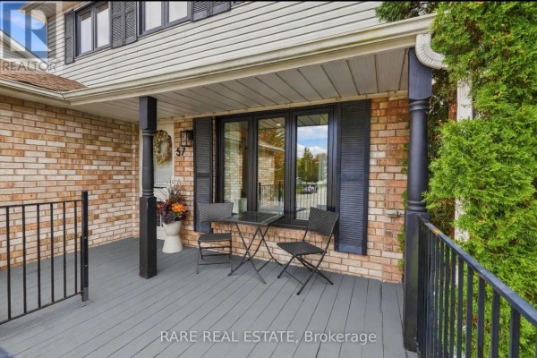 View of a house's front porch with a table, chairs, and black shutters. - 57 Fenwick Avenue, Clarington