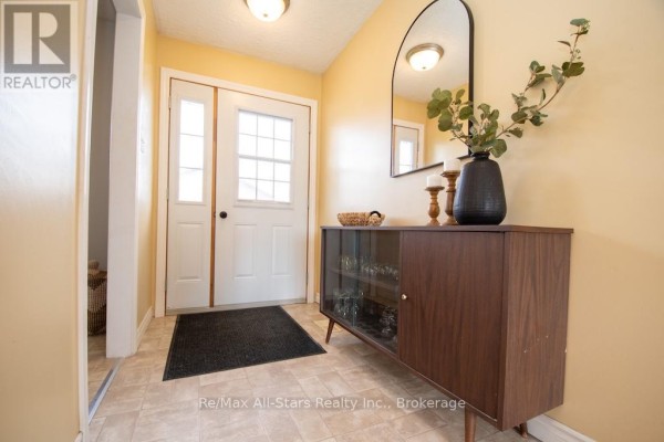 Rear view of brick house with large bay window and wooden deck. - 57 Indian Trail, Kawartha Lakes