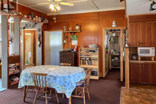 A dining area with a round table, wooden chairs, and wood-paneled walls. - 57 Island View Road, Kawartha Lakes