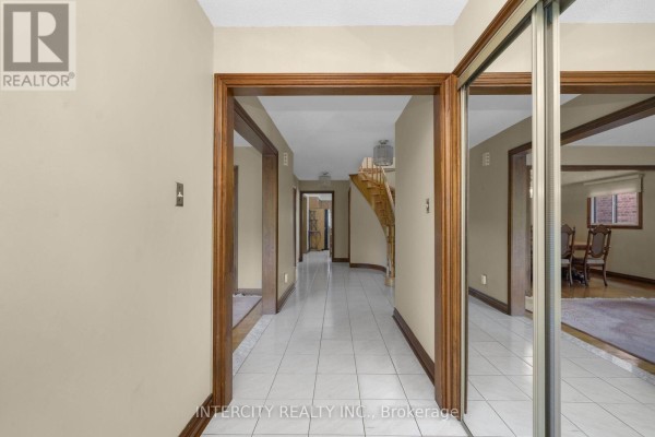 Tiled hallway with wooden trim leading to a staircase and dining area. - 57 Kaiser Drive, Vaughan