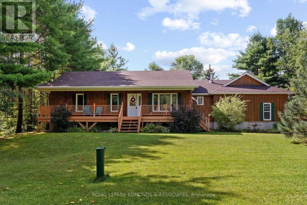 Exterior view of a rustic wooden bungalow with a wrap-around deck. - 57 Krause Street, Laurentian Valley