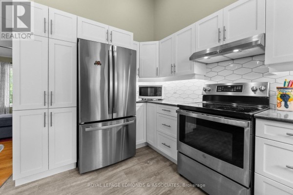 Modern kitchen with stainless steel appliances, white cabinets, and tile backsplash - 57 Krause Street Laurentian Valley
