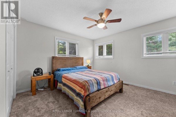Bedroom with wooden bed, striped comforter, and ceiling fan - 57 Krause Street Laurentian Valley