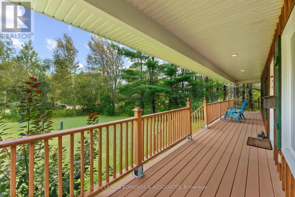 View from a covered wooden porch overlooking a green lawn and mature trees. - 57 Krause Street, Laurentian Valley