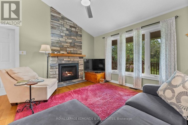 Living room with stone fireplace, vaulted ceiling, and large windows - 57 Krause Street Laurentian Valley