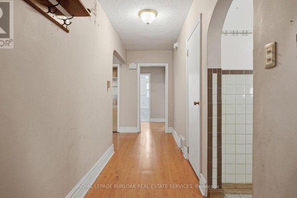 Interior hallway with light wood laminate flooring and archway entrances. - 57 Lambton Avenue, Toronto