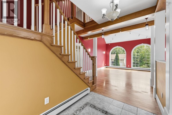 Interior view of a foyer with a wood staircase, yellow and red walls, and arched windows. - 57 Lawlor Crescent, Cole Harbour