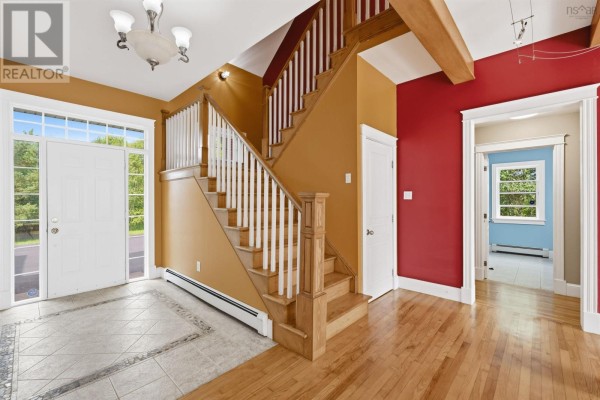 Interior foyer with a white front door, wood staircase, hardwood floors, and a doorway to another room. - 57 Lawlor Crescent, Cole Harbour