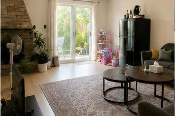 Living room with a stone fireplace, sliding glass doors to the backyard, and two round coffee tables. - 57 Lynch Road, Toronto