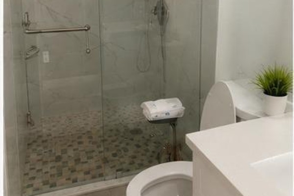 Modern bathroom with a white vanity, toilet, and a glass-enclosed shower with mosaic tile floor. - 57 Lynch Road, Toronto