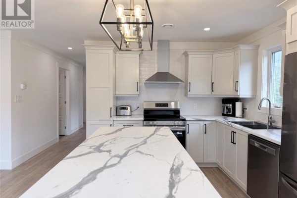 White kitchen with a marble island, stainless steel appliances, and light wood floors. - 57 Pike Street, Pasadena