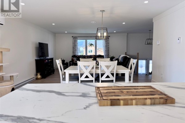 Open concept living and dining area with a white table and chairs, a television, and a cat tree. - 57 Pike Street, Pasadena
