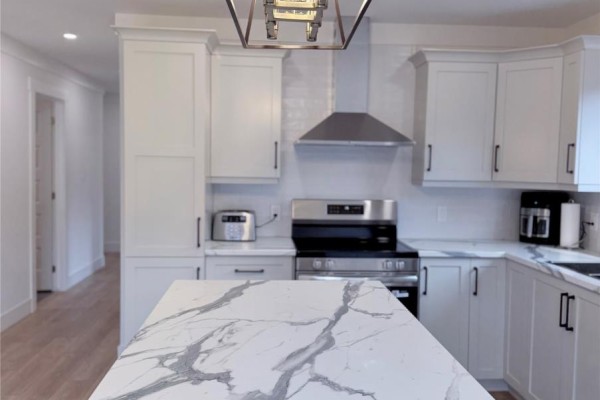 Close-up view of the white kitchen island with marble countertop and a cutting board. - 57 Pike Street, Pasadena