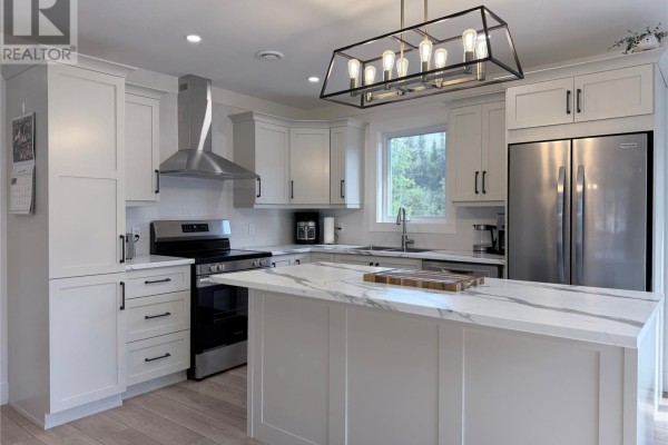 White kitchen with an island, stainless steel refrigerator, dishwasher, and oven with range hood. - 57 Pike Street, Pasadena