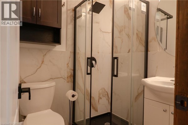 Bathroom with a toilet, white vanity, sink, and a black-framed glass shower stall. - 57 Rupert Court Unit# Upper, Hamilton