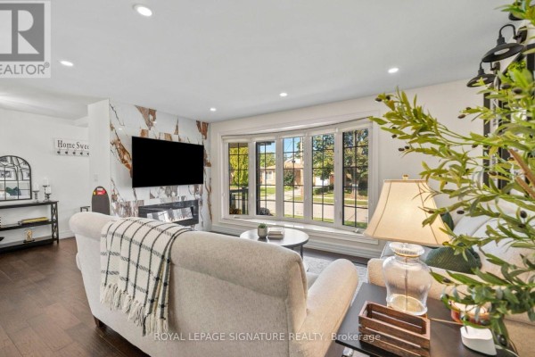 Living room with a bay window, fireplace, and a mounted television. - 57 Sabrina Drive, Toronto
