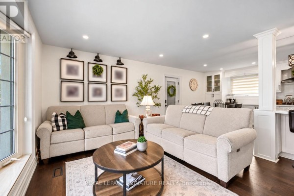 Living room with two sofas, a coffee table, and a view of the kitchen. - 57 Sabrina Drive, Toronto