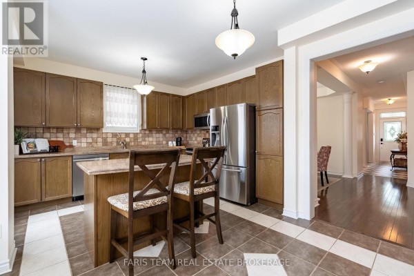 Kitchen looking towards dining area with wood floors and entrance hallway. - 57 Spotted Owl Crescent, Brampton