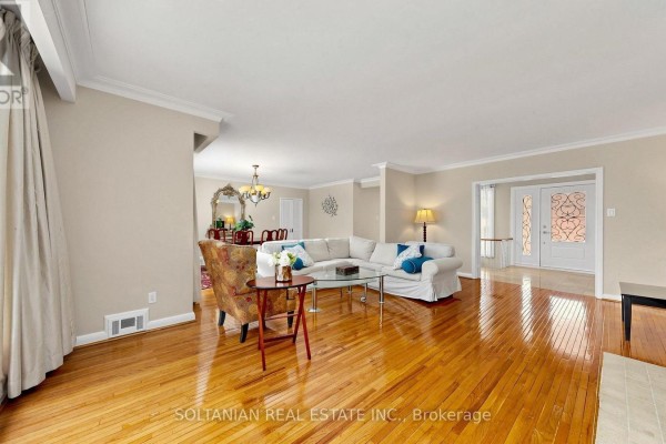 Open concept living and dining area with white furniture, wooden floors, and large windows. - 57 Sumner Heights Drive, Toronto