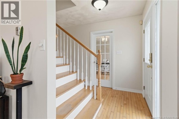 Hallway with wood floor, staircase, and glass-paned door leading to an office. - 570 Mclaughlin, Moncton