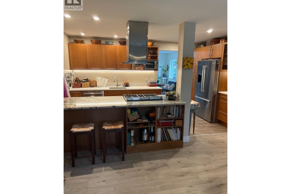 Living area with two leather armchairs, bookshelves, and large windows overlooking the garden. - 5702 Medusa Street, Sechelt