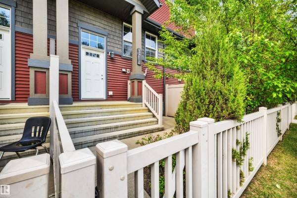 Front entrance stairs and porch of a townhouse, with a white door and beige fence. - 571 Orchards Bv Sw, Edmonton