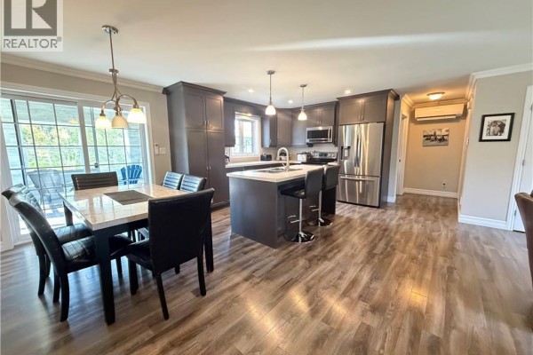 Open concept dining area and kitchen with dark grey cabinets, stainless steel appliances, and island. - 5712 Route 17, Saint Quentin