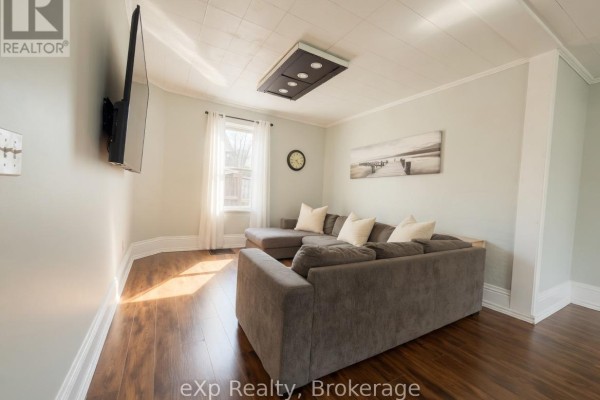 Living room with a sectional sofa, mounted television, and a large window with sheer curtains. - 572 9th Avenue, Hanover