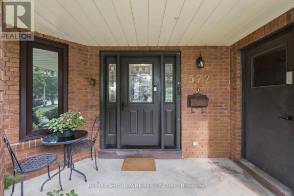 Covered brick front porch with a dark brown double door and decorative sidelights. - 572 Harmony Avenue, Burlington