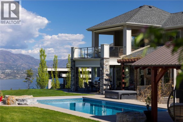 View of a bridge crossing a wide blue lake with forested hills beyond. - 5723 Jasper Way, Kelowna