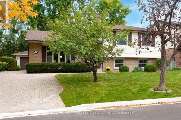 View of the property exterior from the street, showcasing the lawn and trees. - 573 Jamaica Court, London South